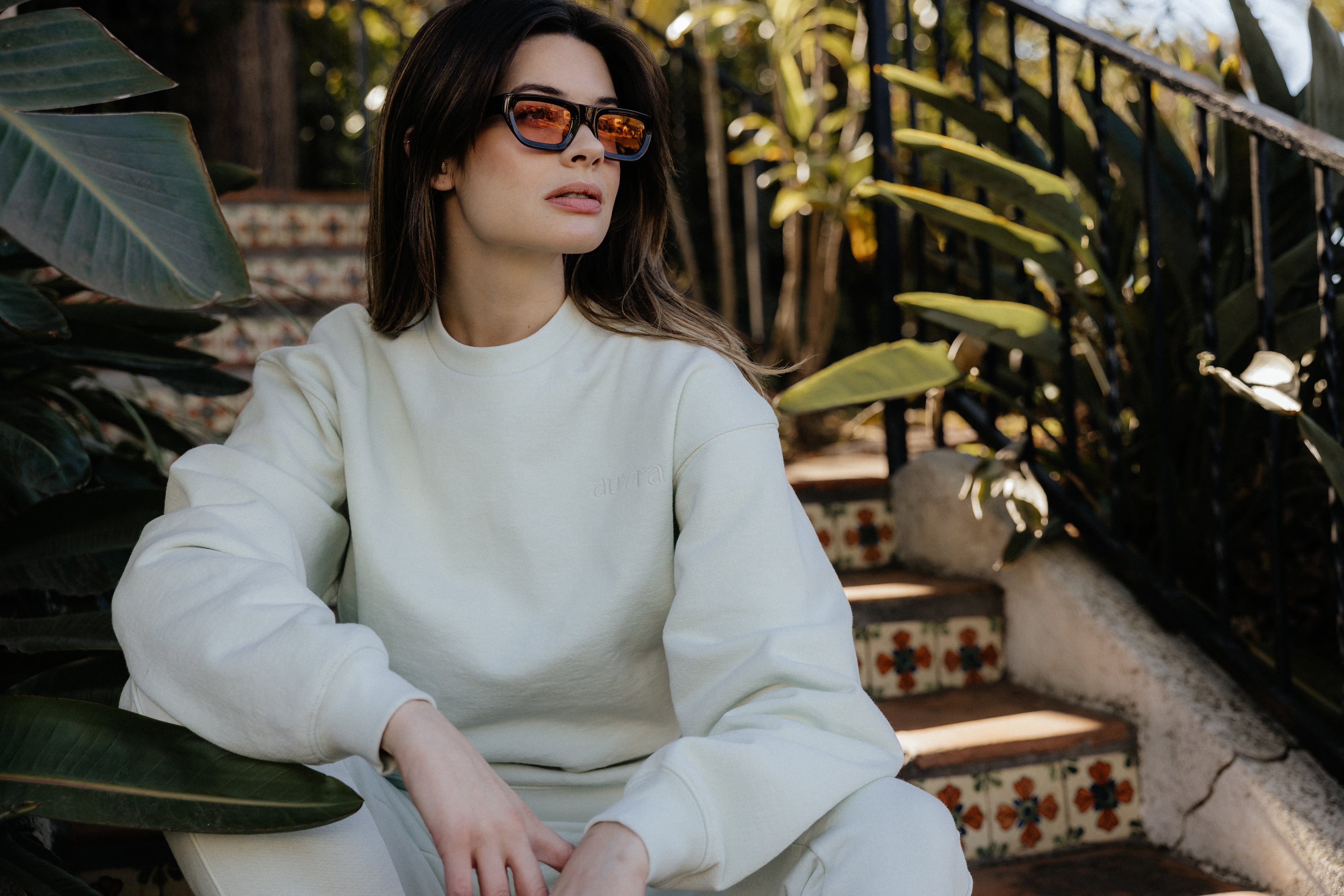 Woman in trendy sunglasses wearing luxury loungewear.