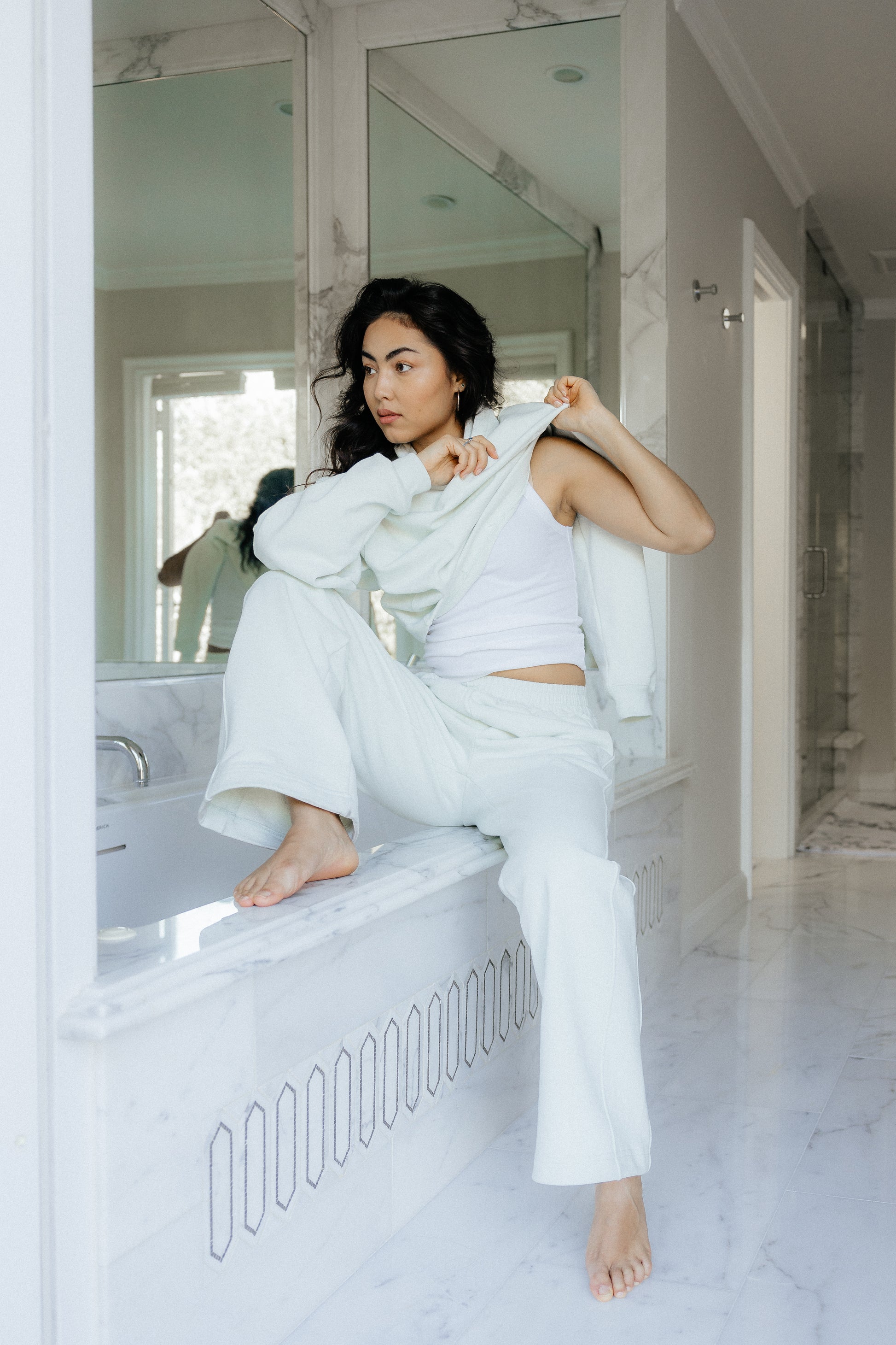 Woman in bathroom putting on luxury loungewear.