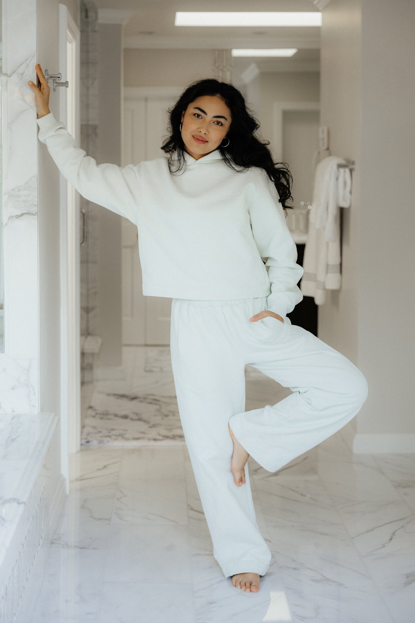 Woman in bathroom in sage colored luxury loungewear set.